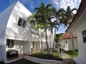 a white house with palm trees in front of it at Heartland Hotel Serviced Rooms & Apartments. in Panglao