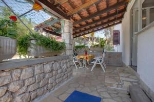 eine Terrasse mit einem Tisch und Stühlen an einer Steinmauer in der Unterkunft Apartment Simpatico in Čunski