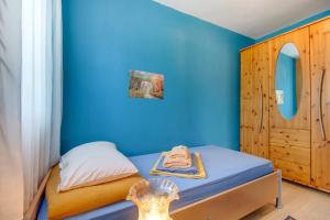 een kleine slaapkamer met blauwe muren en een bed bij Apartment Simpatico in Čunski