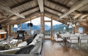 a living room with a couch and a dining room with mountains at Les 3 Chalets Courchevel in Courchevel