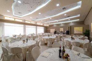 a banquet hall with white tables and white chairs at Hotel Terme Pellegrini in Montecatini Terme