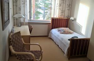 a bedroom with a bed and a desk and a window at Club House Hotelli Kaipolan Ranta in Jämsä