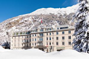 un bâtiment recouvert de neige avec une montagne en arrière-plan dans l'établissement Sporthotel Pontresina, à Pontresina