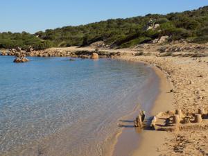 a sandy beach with some rocks and water at Vi.Co House in La Maddalena