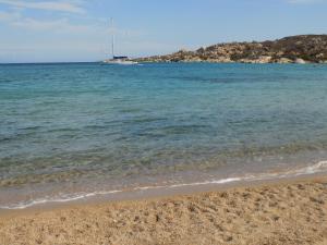 a beach with the ocean and a boat in the distance at Vi.Co House in La Maddalena