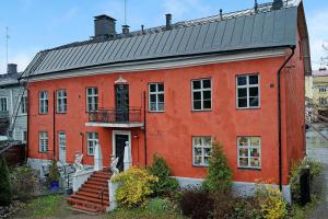 een oranje gebouw met een zwart dak en een trap bij Remuganes suite - Porvoon Linna in Porvoo