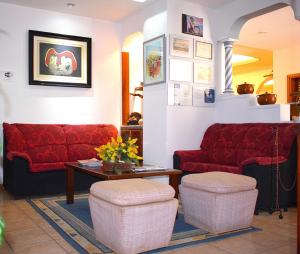 a waiting room with red couches and a table at Hotel Ida Inés in Frontera