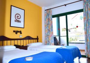 two beds in a room with yellow walls and a window at Hotel Ida Inés in Frontera
