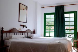 two beds in a white room with a window at Hotel Ida Inés in Frontera