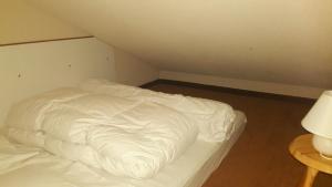 ein unmaskiertes Bett mit weißer Bettwäsche in einem Zimmer in der Unterkunft Ski Sun 3315 in Manigod