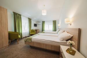 カリマネシュティにあるHotel DADA Termalの大きなベッドと緑のカーテンが備わるホテルルームです。