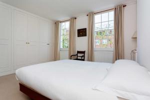 a bedroom with a large white bed and a window at Veeve - Sloane Square Hideaway in London