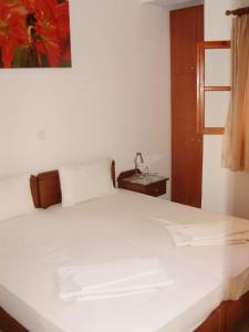 a bedroom with a white bed with a table and a window at Tarsanas Beach in Kokkari