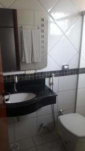 a bathroom with a sink and a mirror and a toilet at Nioja Hotel in Itumbiara