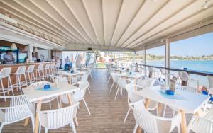 a restaurant with white tables and chairs on a cruise ship at Filoxenia Beach in Tsilivi