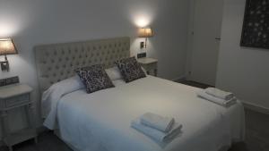 a bedroom with a large white bed with towels on it at GUESTING VELAZQUEZ in Cádiz