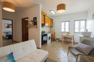 a living room with a white couch and a kitchen at By the C house in Vila Nova de Milfontes