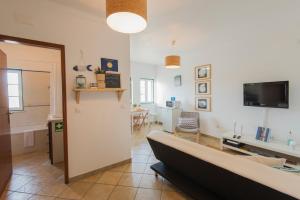 a living room with a couch and a tv in it at By the C house in Vila Nova de Milfontes