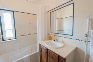 a bathroom with a sink and a mirror and a tub at By the C house in Vila Nova de Milfontes +14 photos
