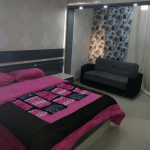 een slaapkamer met een bed en een bank bij City Stars Two Bedroom in Caïro