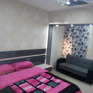 een slaapkamer met een roze bed en een bank bij City Stars Two Bedroom in Caïro