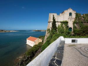 a castle on the side of a body of water at By the C house in Vila Nova de Milfontes