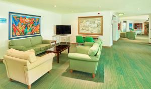 a living room with couches and chairs and a tv at Hotel Baia Grande in Albufeira