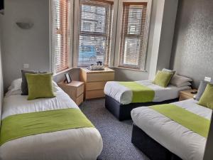 Cette chambre comprend 2 lits avec des draps verts et blancs. dans l'établissement Chelsea Hotel, à Bournemouth