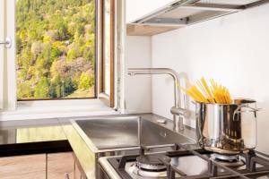 a kitchen with a sink and a stove with a window at HelloChalet - Maison Rue de la Neige - Family Ski Holiday walking distance skirun and gondola in Valtournenche