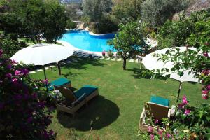 un patio con 2 sillas, una sombrilla y una piscina en Sandima 37 Suites Hotel, en Yalıkavak