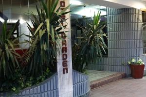 un panneau d'hôtel avec des plantes devant un bâtiment dans l'établissement Hotel Garden, à San Miguel de Tucumán