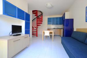 een woonkamer met een blauwe bank en een keuken bij Parco Hemingway in Lignano Sabbiadoro