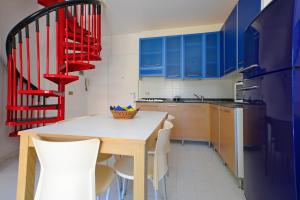 cocina con armarios azules, mesa y sillas en Parco Hemingway, en Lignano Sabbiadoro