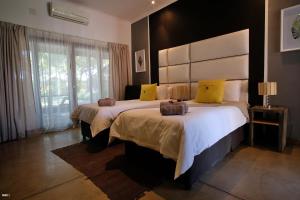 a bedroom with two beds and a large window at Cu Guest House in Phalaborwa