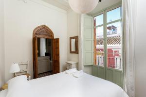 1 dormitorio con cama blanca y ventana en Teatro Suites Málaga, en Málaga