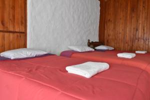 2 camas con sábanas rojas y toallas blancas. en Oasis Paraiso Ecolodge, en Cabanaconde