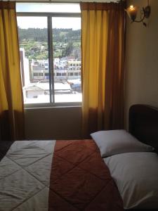 a bedroom with a bed and a window with a view at Samana Hostal in Otavalo