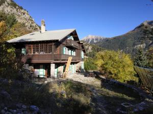a house on a hill with mountains in the background at Appartement RDC chalet 55m2 in Briançon