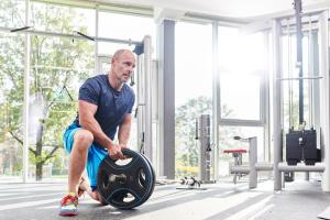 a man sitting on a wheel in a gym at Val Blu Sport | Hotel | SPA in Bludenz