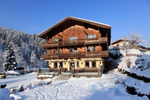 un gran edificio de madera con nieve en el suelo en Gasthof Zum Lendwirt, en Westendorf