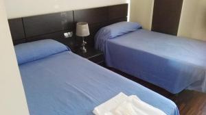 two beds in a hotel room with blue sheets at albergue rural vía de la plata in Casar de Cáceres