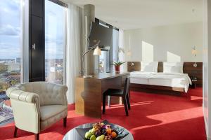 a hotel room with a desk and a bed and a table at Empire Riverside Hotel in Hamburg