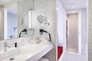 a white bathroom with a sink and a shower at Empire Riverside Hotel in Hamburg