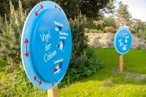 two signs in a garden with arrows on them at Kapitänsweg 07 in Ostseebad Karlshagen +11 photos