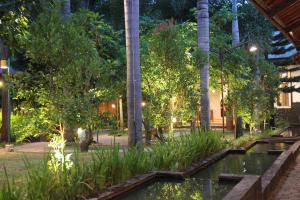 a garden with a pond and trees at night at Bamboe Inn Homestay in Bandar Lampung