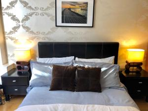 una camera da letto con un letto con cuscini e due lampade di Luxury apartment in Central London, Mida Vale a Londra
