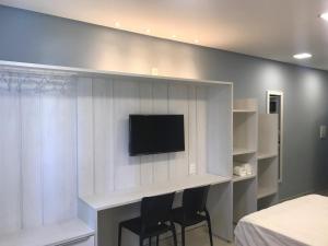 a room with two chairs and a tv on a wall at APART HOTEL MARINAS TAMANDARÉ - Flat 104 in Tamandaré
