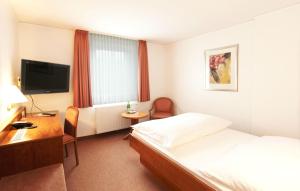 a hotel room with a bed and a desk and a television at Landhaus Michels garni in Kaarst