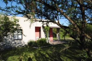 a white house with a red door and a tree at Casas del Champaquí in San Javier