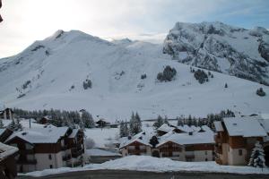 a village covered in snow with a mountain in the background at Mont Blanc Soleil E17 in Manigod